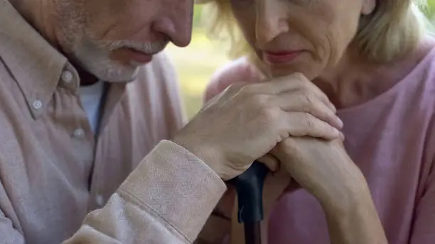 Elderly couple leaning on walking stick, strong marriage, support of pensioners