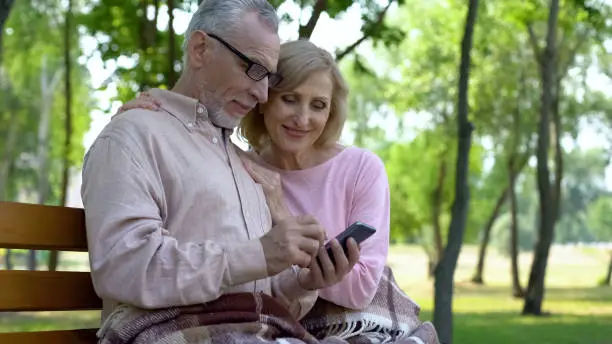 Senior husband and wife using smartphone, pension fund application, gadget