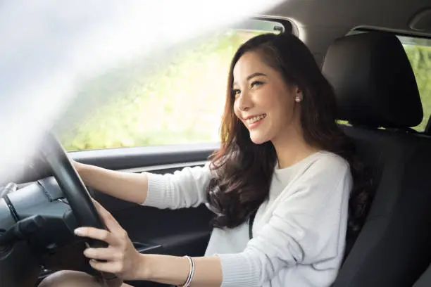 Photo of Asian women driving a car and smile happily with glad positive expression during the drive to travel journey, People enjoy laughing transport and relaxed happy woman on roadtrip vacation concept