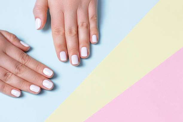 istock Female hand with white manicure on a on pastel colored background with copy space, top view 1086802040