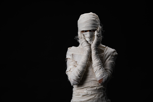 Studio shot portrait  of young man in costume  dressed as a halloween  cosplay of scary mummy pose like a headache acting on isolated black background.