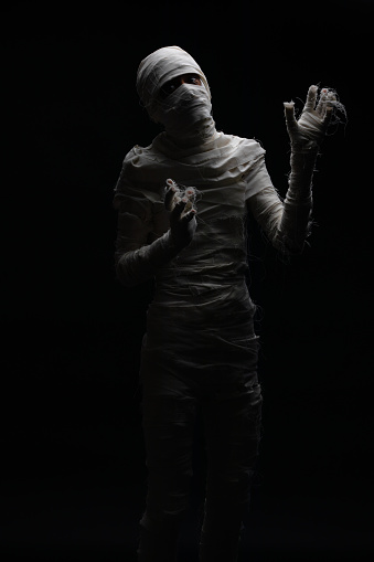 Studio shot portrait  of young man in costume  dressed as a halloween  cosplay of scary mummy pose like a clamber acting on isolated black background.
