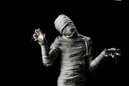 Studio shot portrait  of young man in costume  dressed as a halloween  cosplay of scary mummy pose like a clamber acting on isolated black background