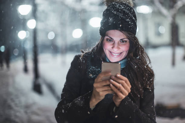 istock Young woman using smartphone in snow 1086803994