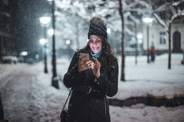 istock Young woman using smartphone in snow 1086804012