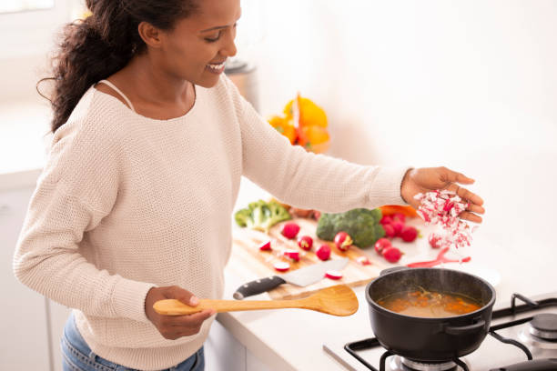 mujer añadiendo rábano picado en el caldo hirviendo, cocinar la sopa vegetal. - cooking domestic kitchen vegetable soup fotografías e imágenes de stock