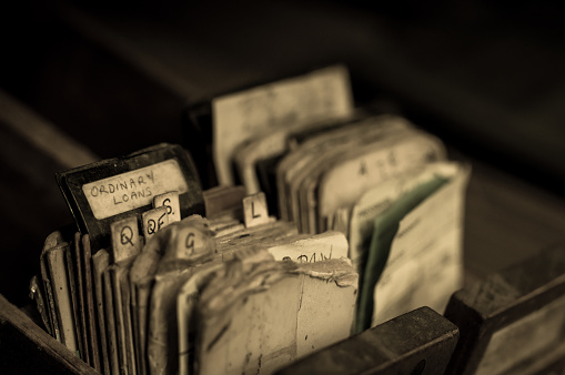 Index cards and borrowing slips in the drawer of an abandoned library card catalogue cabinet.  Selective focus.  Belfast, Northern Ireland.
