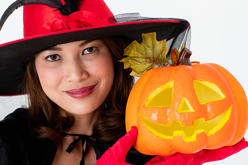 Woman in red costume holding pumpkin, portrait studio shot on white background.