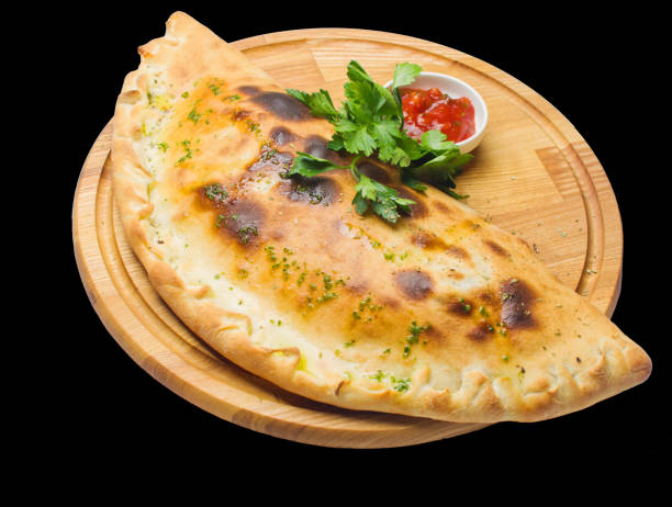 calzone pizza na okrągłej drewnianej desce odizolowanej na czarnym tle - pizza pastry crust stuffed cheese zdjęcia i obrazy z banku zdjęć