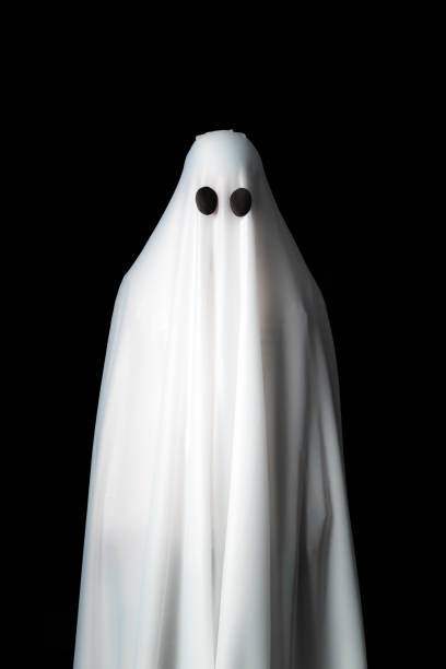 istock Someone covered with white cloth with big black eyes on black background look like ghost in night. Concept for funny playing in halloween festival 1086817678