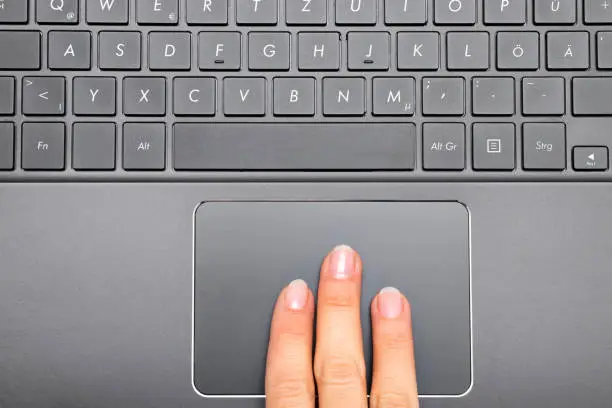 Photo of Three fingers of a woman on Notebook Touchpad