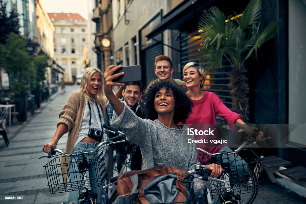 Friends Riding Bicycles In A City Friends Riding Bicycles In A City. Cycling in pedestrian zone and making selfie. Friendship Stock Photo