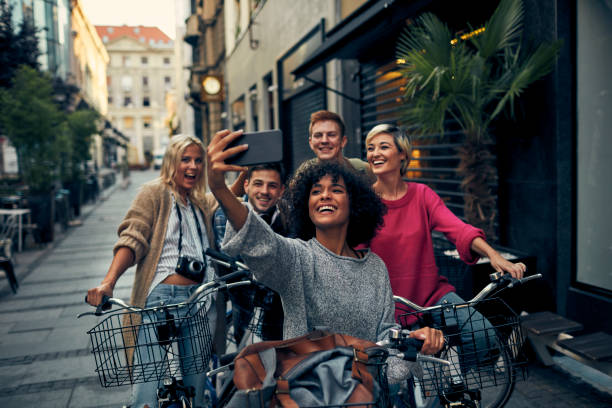 Friends Riding Bicycles In A City Friends Riding Bicycles In A City. Cycling in pedestrian zone and making selfie. gen z stock pictures, royalty-free photos & images