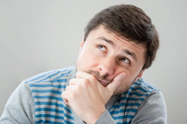 istock Thoughtful handsome bearded man in a striped sweater leaning his head against his hand looking up 1086845040
