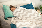 Woman sleeping tucked in a warm blanket