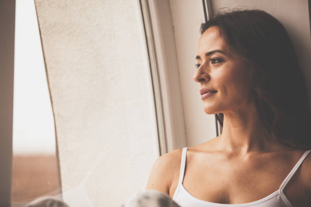 istock Pensive woman looking through the window 1086847906