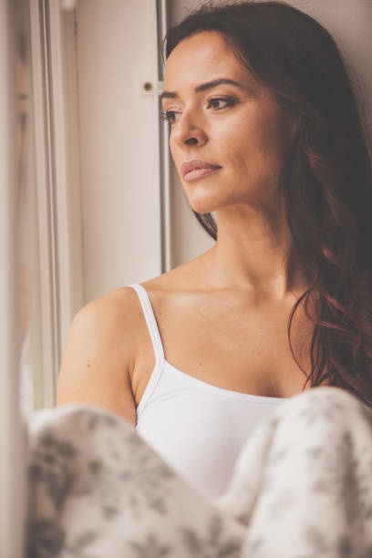 istock Pensive woman looking through the window 1086847910
