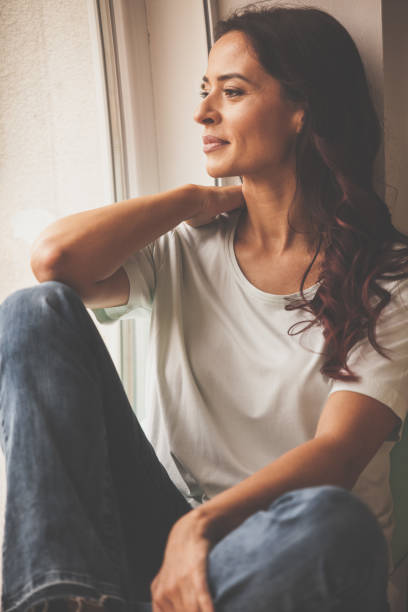 istock Pensive woman looking through the window 1086847980
