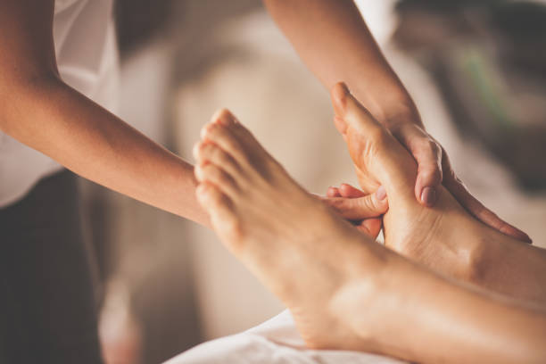 Reflexologist applying pressure to foot with thumbs Close-up shot of massage therapist doing reflexology massage to female client at spa. foot spa treatment stock pictures, royalty-free photos & images