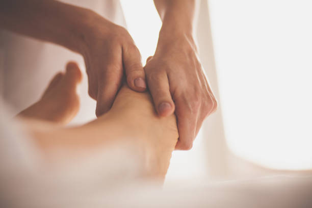 massaggiatore massaggiatrice massaggiando i piedi della donna - foot massage foto e immagini stock