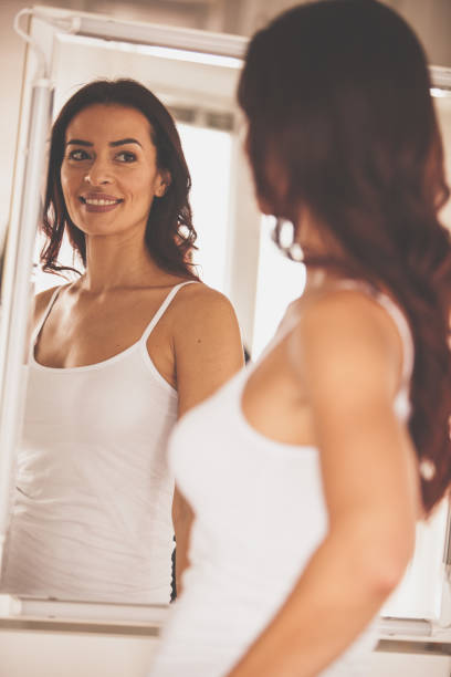 istock Satisfied woman looking at her reflection in the mirror 1086851924