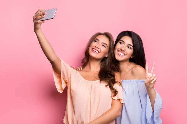 istock Two cheerful women taking selfie over pink background 1086852124