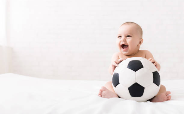 newborn baby sitting with soccer ball on bed - fashion model small one person happiness imagens e fotografias de stock