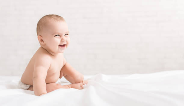 istock Beautiful laughing baby sitting on white background 1086859244