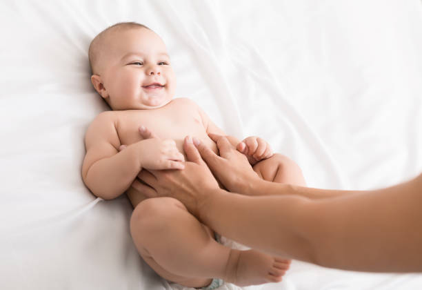 masseur massage ventre de bébé lors des coliques - abdomen women massaging human hand photos et images de collection