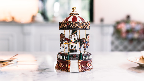 Miniature Carousel Toy over white marble top table with blur background.