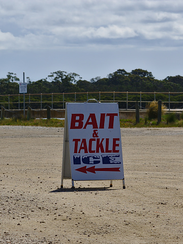 Bait and Tackle Ice Sign on gravel ground during the day