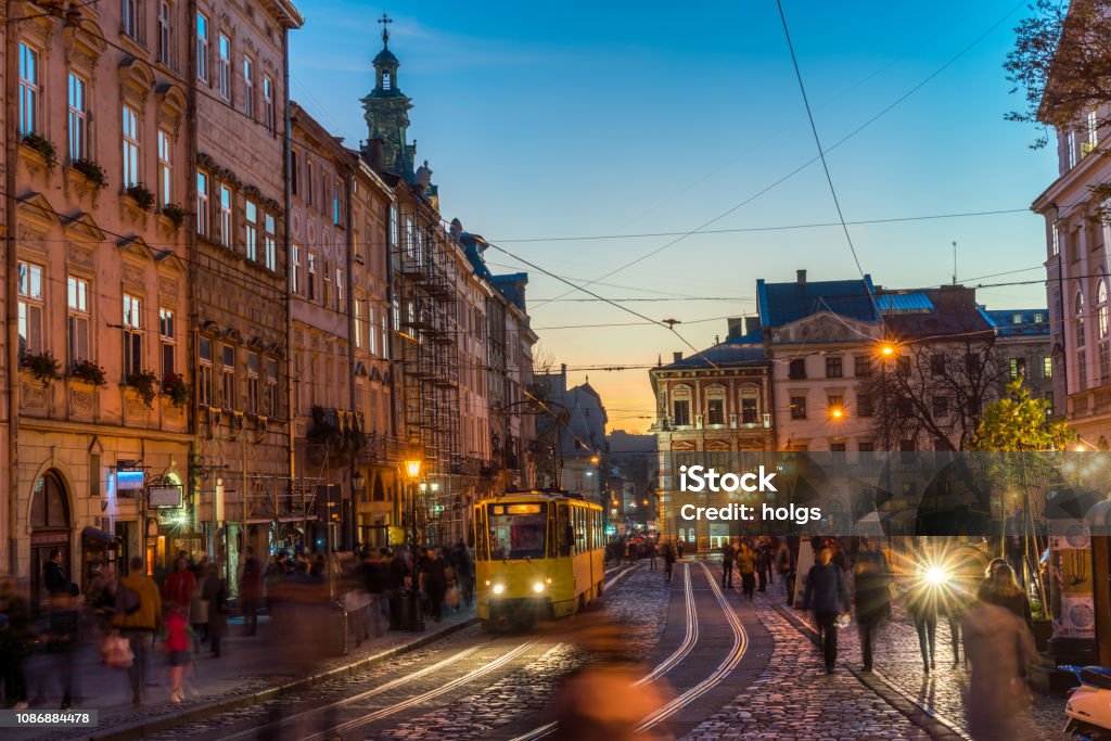 Lviv Town Square at nIght, Ukraine, Europe Lviv, Ukraine - October 31, 2018:  view showing people walking around Lviv Old town square, building apartments, trams in the tramway and church tower can be seen on the background at night Lviv Stock Photo