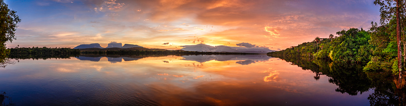 Early  morning panoramic view at sunrise of the Carrao river in the Canaima National Park, Venezuela. Group of tepuis, from left to right: Kurun, Kusary, Kurawaik and Tok Pochik. Canaima is a world known place for the beauty of nature and countless waterfalls. Canaima is visited for tourist all around the world during all year round. During rainy season navigation on the Churun river is possible to visit the Angel falls, the tallest waterfall in the world with 976 mt of water free fall.