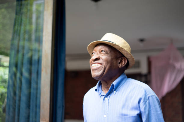 superior afro mirando por la ventana - pensive senior adult looking through window indoors fotografías e imágenes de stock