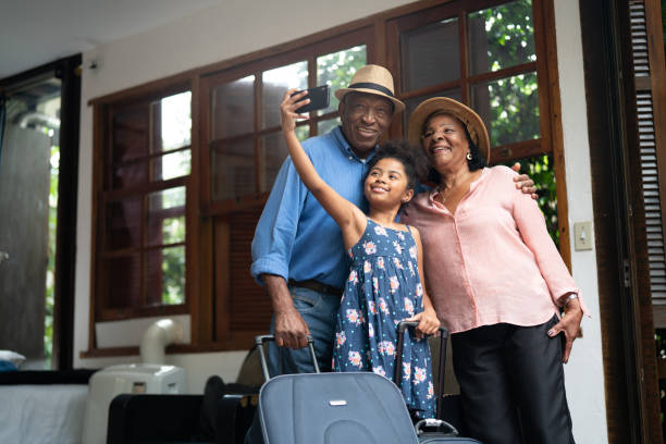 grandparents and granddaughter taking selfies after arriving in a hotel - senior adult technology child internet imagens e fotografias de stock