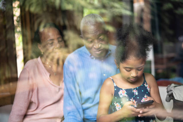 istock Grandparents and Granddaughter Using Mobile Phone Through the Window 1086889700