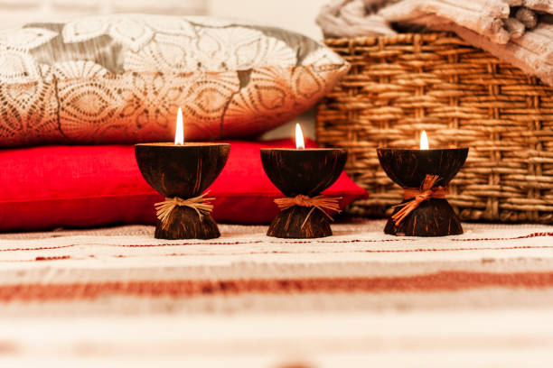 istock Burning spa aroma candles in coconut shell, pillows and plaid, cozy home interior background 1086896230