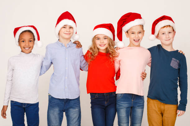 istock Happy children in santa hats hugging over background 1086896984