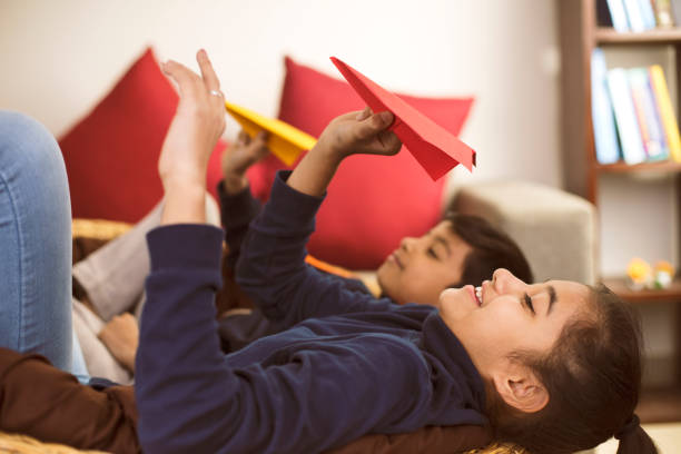 istock Children throwing paper airplane at home 1086904448