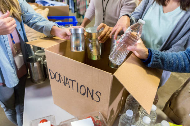 istock People place canned food donations into box 1086922394