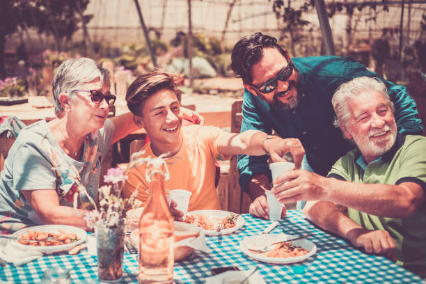 祖父から父と孫を祝うと健康的なライフ スタイルのための代替屋外自然レストランで一緒に食事を楽しんでまで美しい白人家族のグループです。イタリアのパスタ料理と幸福概念 - 食べる 写真 ストックフォトと画像