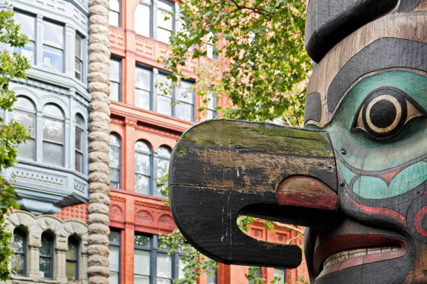 Totem Pole - Pionner Sqaure - Seattle Pioneer square park Totem pole - a National Historic Landmark - has been in its current location since 1938 when the Tlingit tribe carved and gave it to the city of Seattle. This was a replacement for the original pole - destroyed in a fire - which was stolen from the tribe in 1899. pacific northwest totem poles stock pictures, royalty-free photos & images