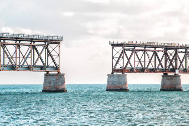 Old, rusted, rust, rusty derelict Bahia Honda rail road in state park, clouds, cloudy blue sky at sunset, dusk, horizon, ocean, sea water