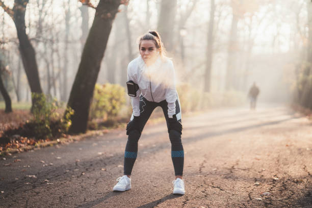Sportswoman taking a breath after jogging Young woman resting after running breath vapor stock pictures, royalty-free photos & images