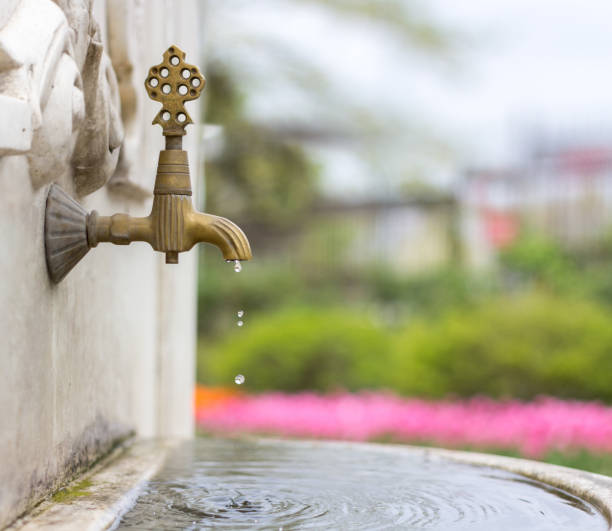Water pouring from a tap in an old fountain stock photo