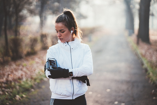 Young woman starting mobile app for sports training before jogging