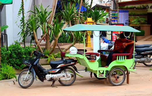 Siem Reap, Cambodia - Mart 27, 2018: Tuk Tuk taxi on city street waiting for passengers. Tuk Tuk popular tourism transport and symbol of Cambodia culture