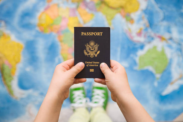 child's hand holding us passport. map background. ready for traveling. open world. - passport usa american culture front view imagens e fotografias de stock