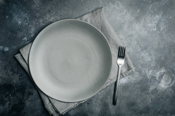istock Gray empty plate (ceramic) with fork on gray stone background. Gray minimalism concept. Copy space. 1087000070