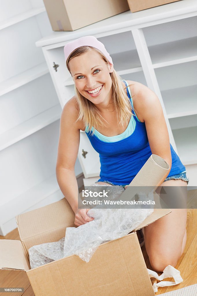 Atrakcyjna kobieta rozpakowaniu pudełka na podłodze - Zbiór zdjęć royalty-free (Blond włosy)